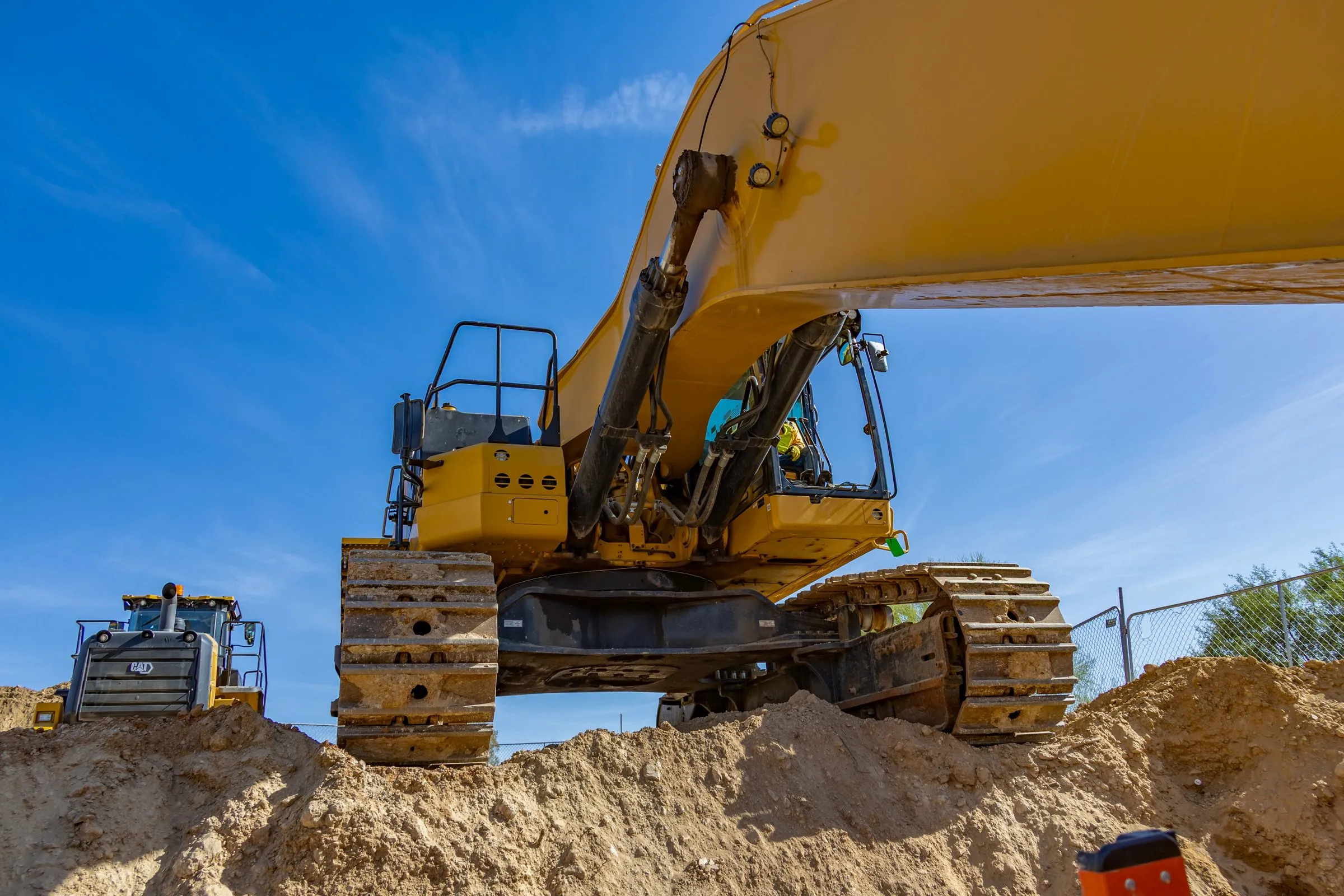 Low-angle aerial of an excavator on a dirt mound