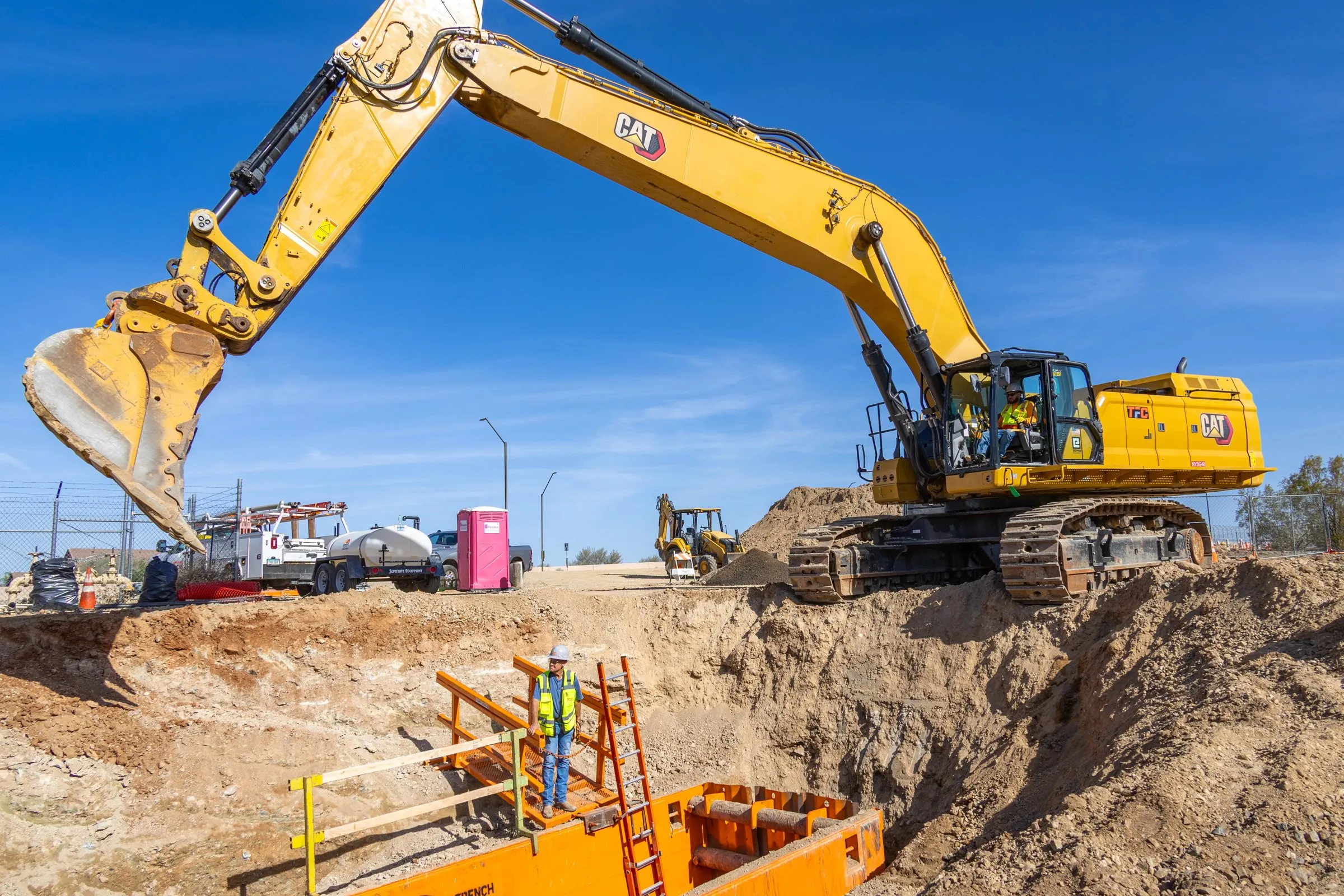 Aerial photo of an excavator digging beside a trench on an active site